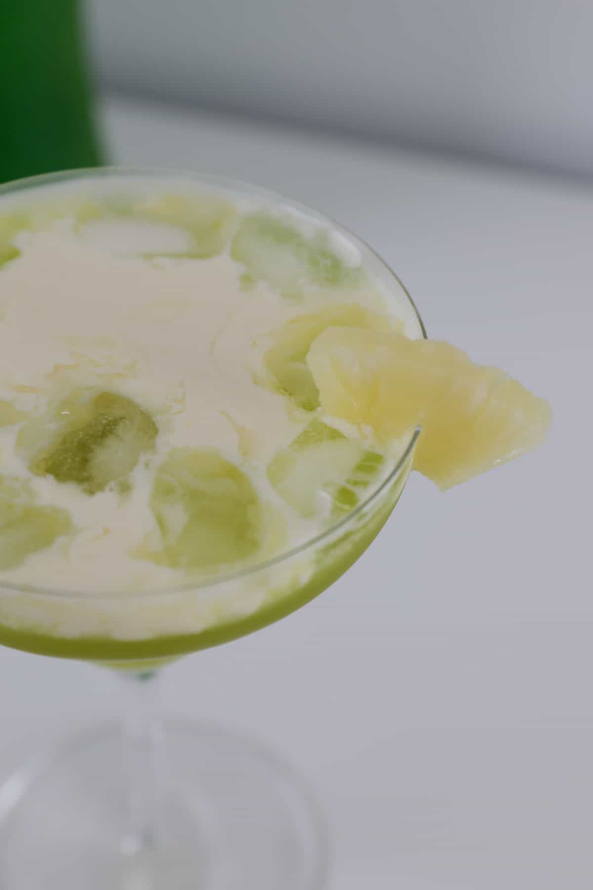An overhead shot of cream on top of a midori cocktail.