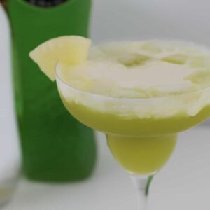 A green cocktail topped with cream.
