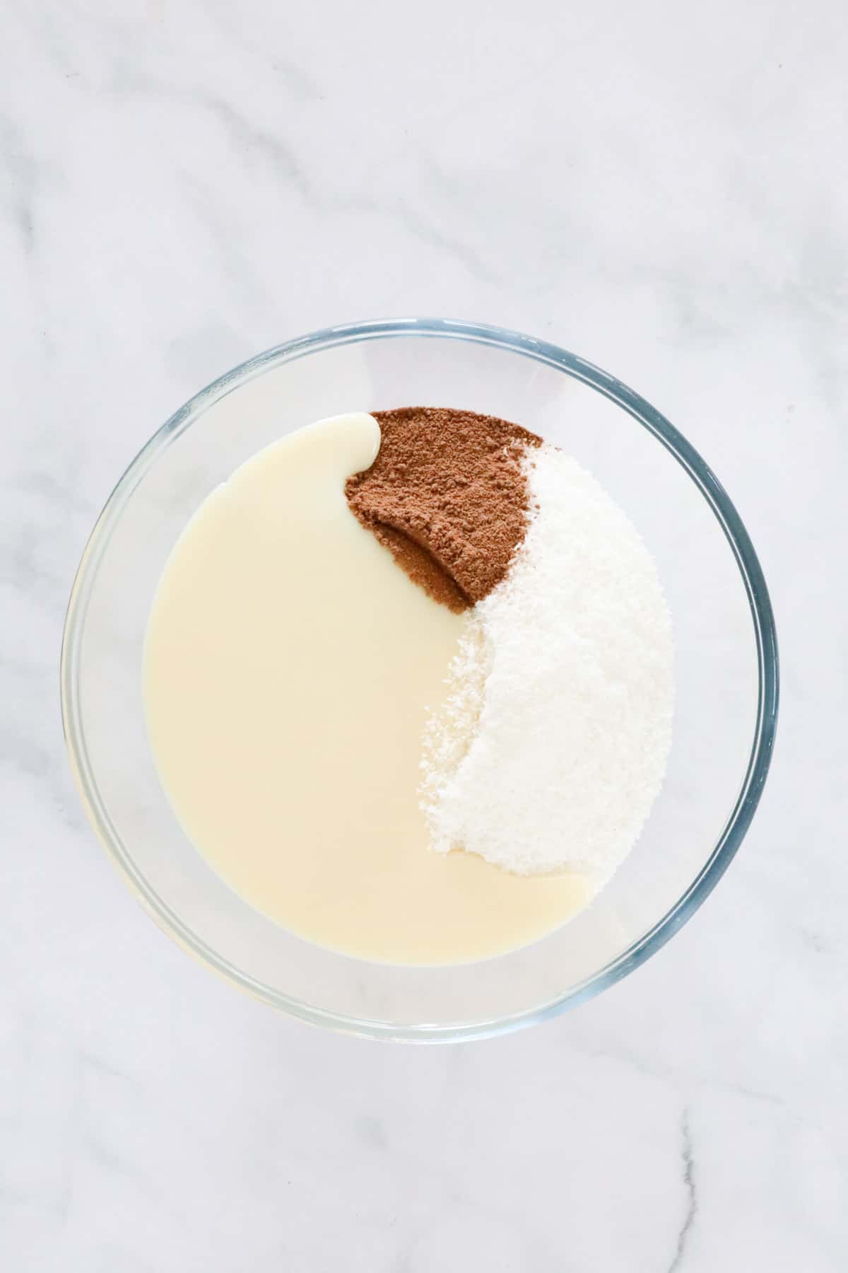 Condensed milk, coconut and milo in a glass bowl.