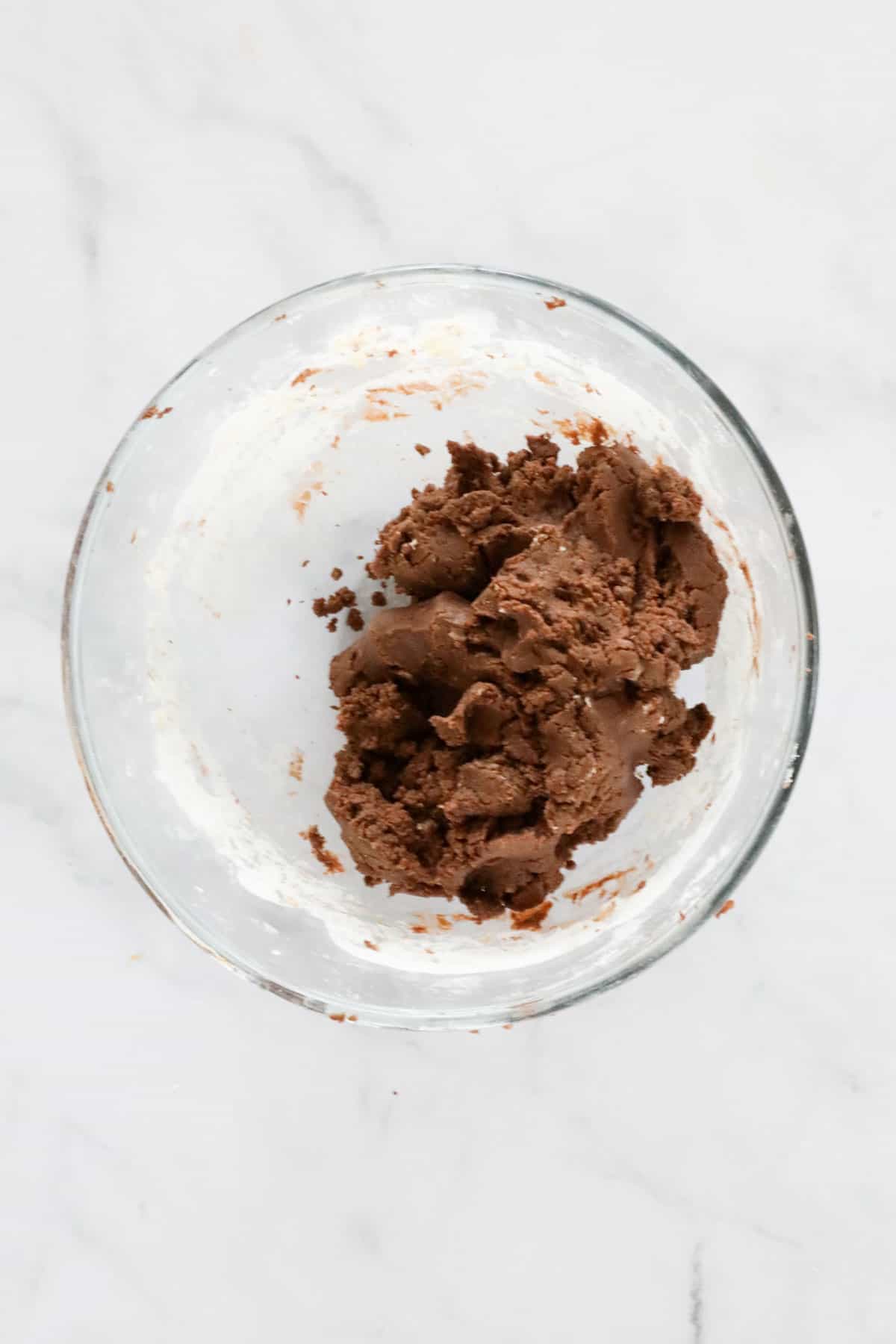 A chocolate coloured dough in a glass bowl.
