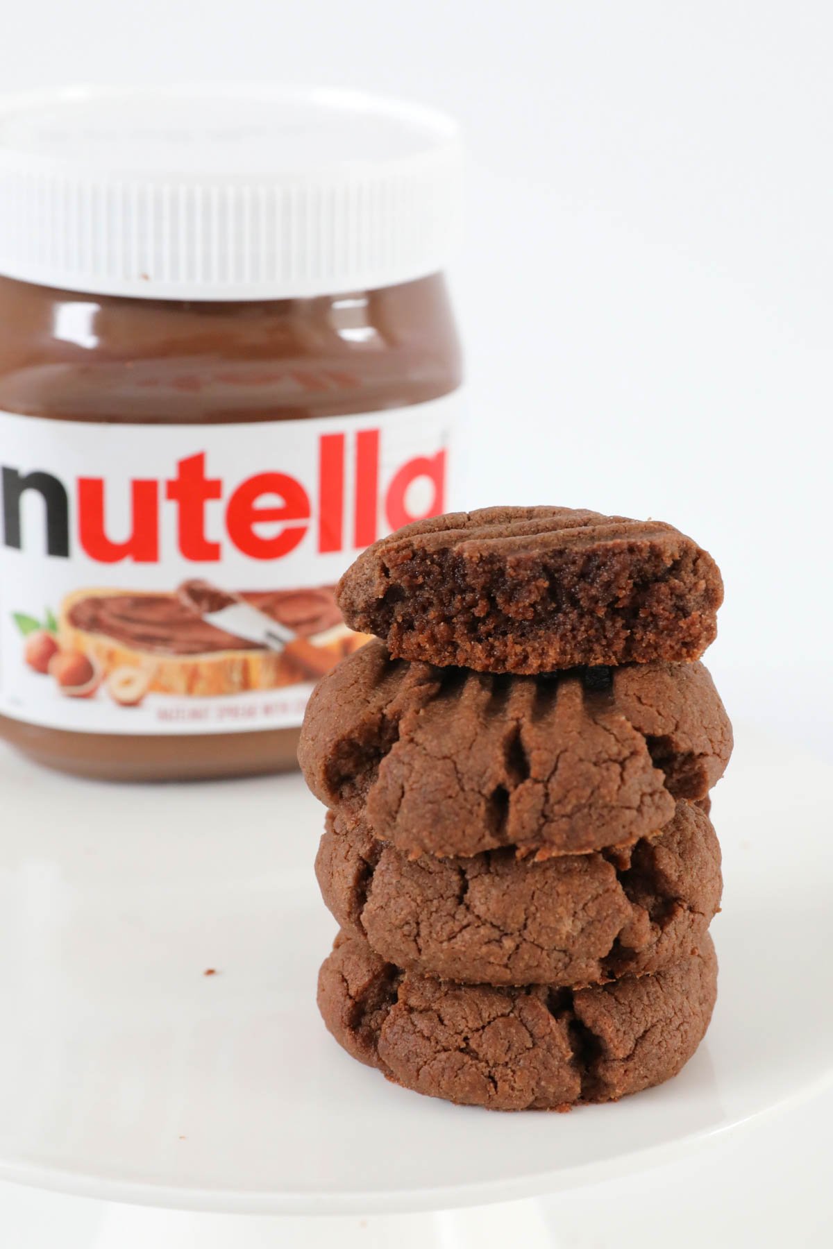 A stack of chocolate cookies next to a jar of Nutella.
