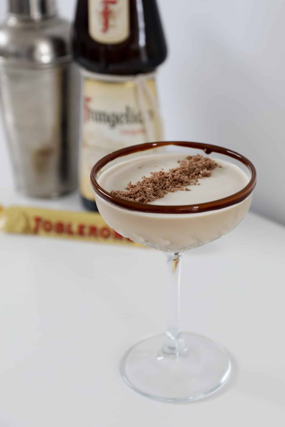 A Toblerone cocktail decorated with grated Toblerone, in a glass.