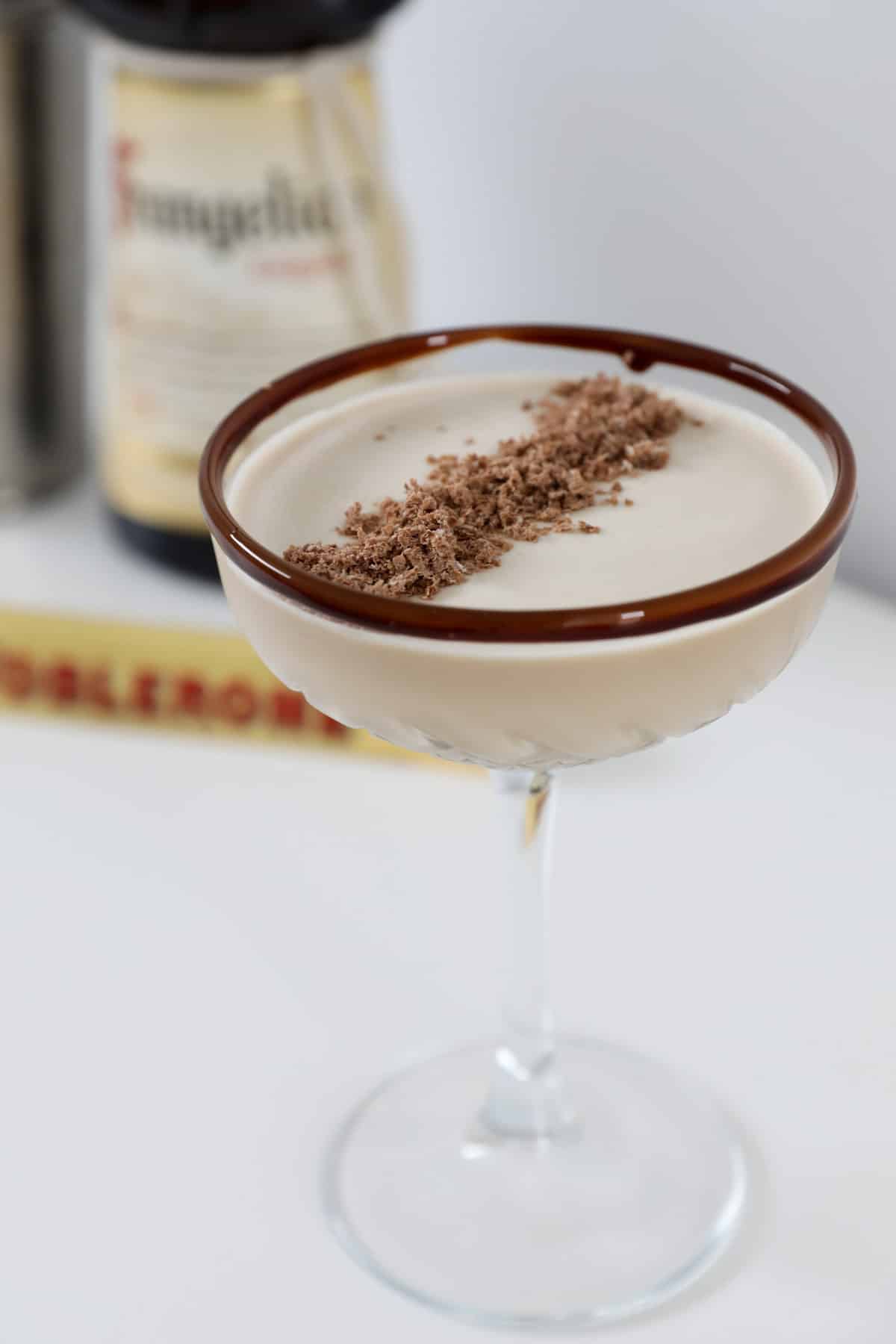 A close up of a chocolate rimmed glass filled with a creamy cocktail.