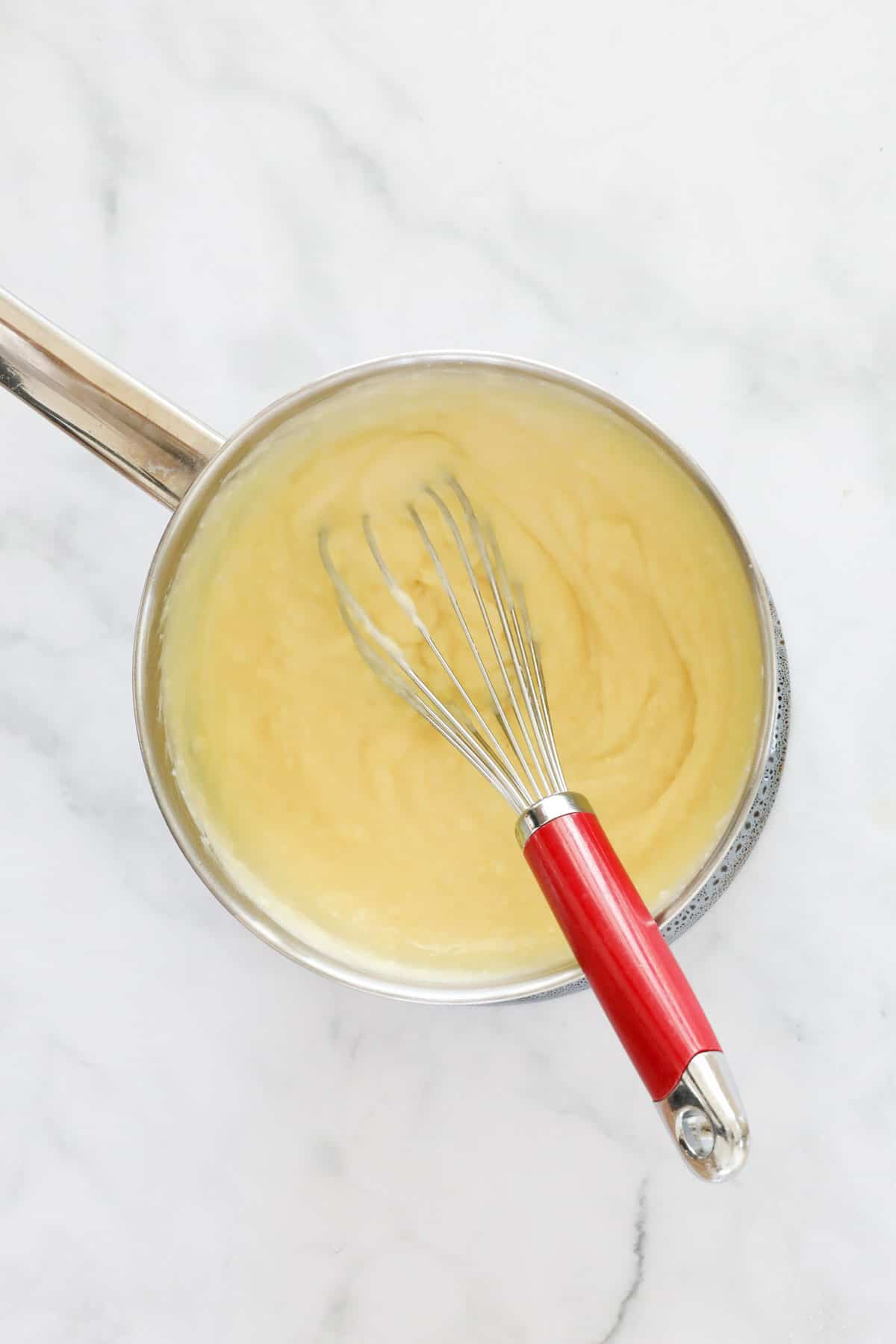 Custard being whisked in a saucepan.