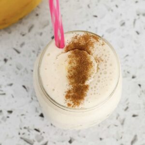 An overhead shot of a banana smoothie with a pink straw.