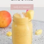 A creamy mango smoothie served in a glass jar with a pink straw.