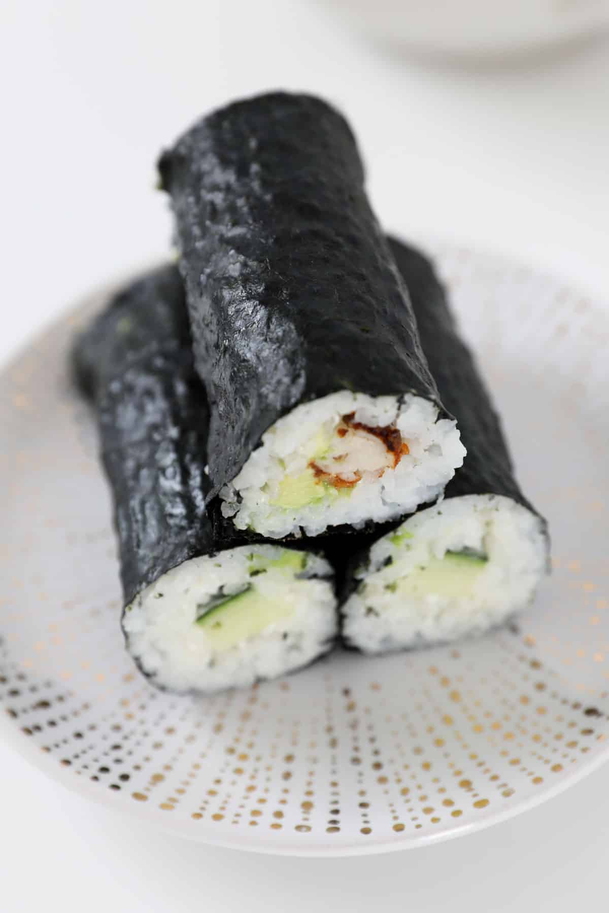 Three pieces of hand rolled sushi on a plate.