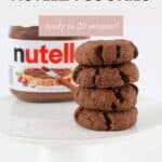 A stack of four cookies in front of a jar of Nutella.