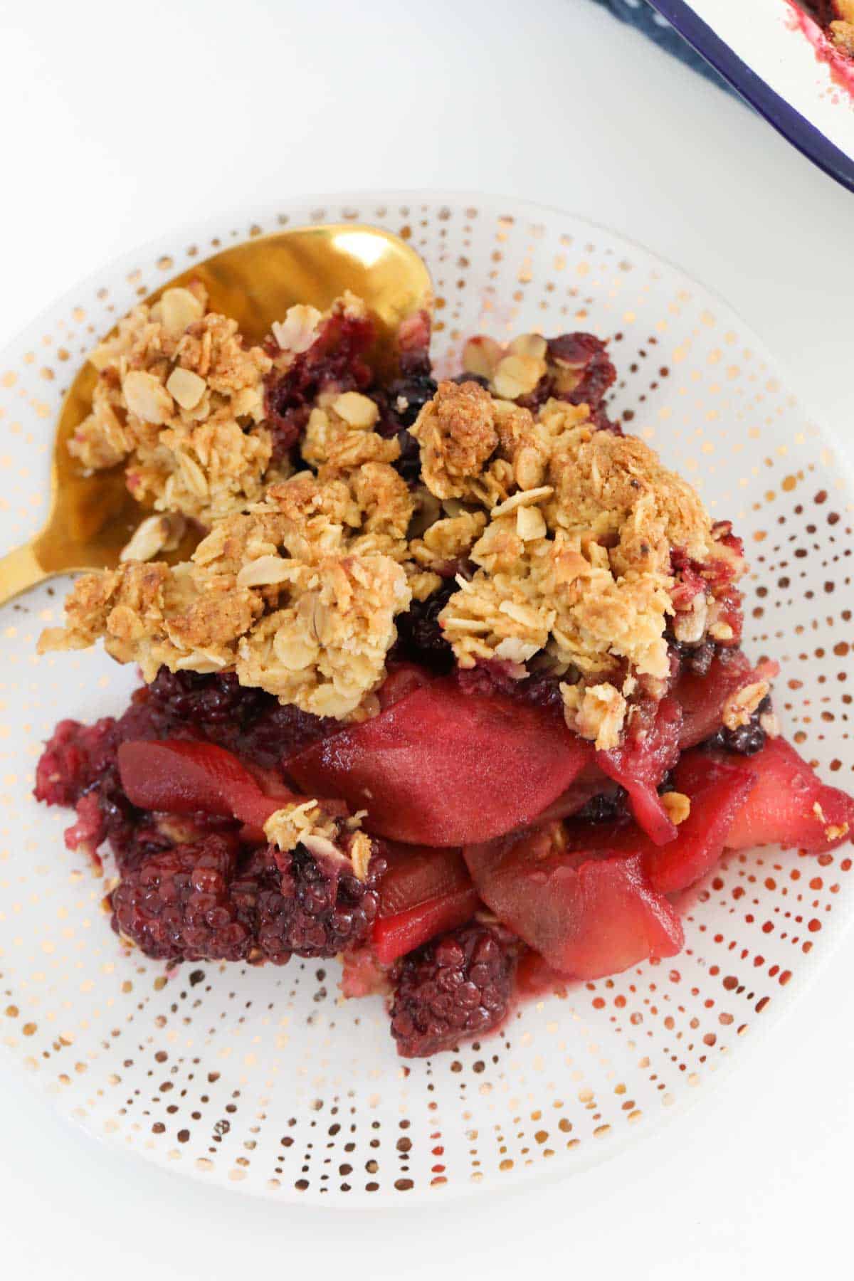 A plate of crunchy apple crisp with blackberries.
