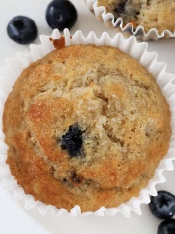 An overhead shot of a crunchy sugar topped banana muffin with blueberries.