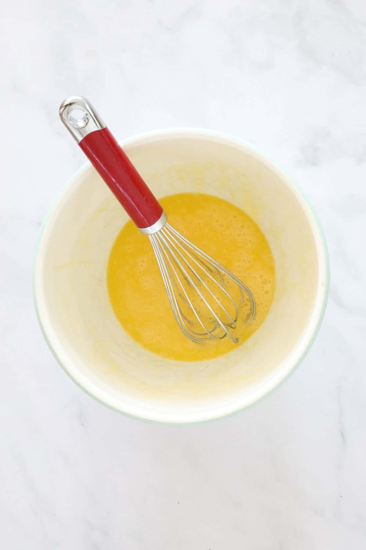 Melted butter in a mixing bowl, with a whisk.