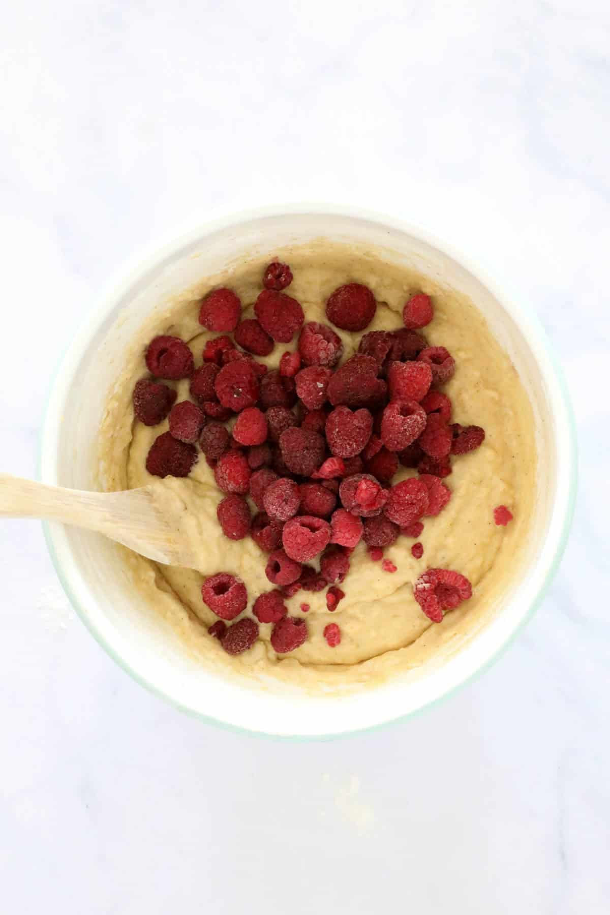 Raspberries added to mixture in a white bowl.