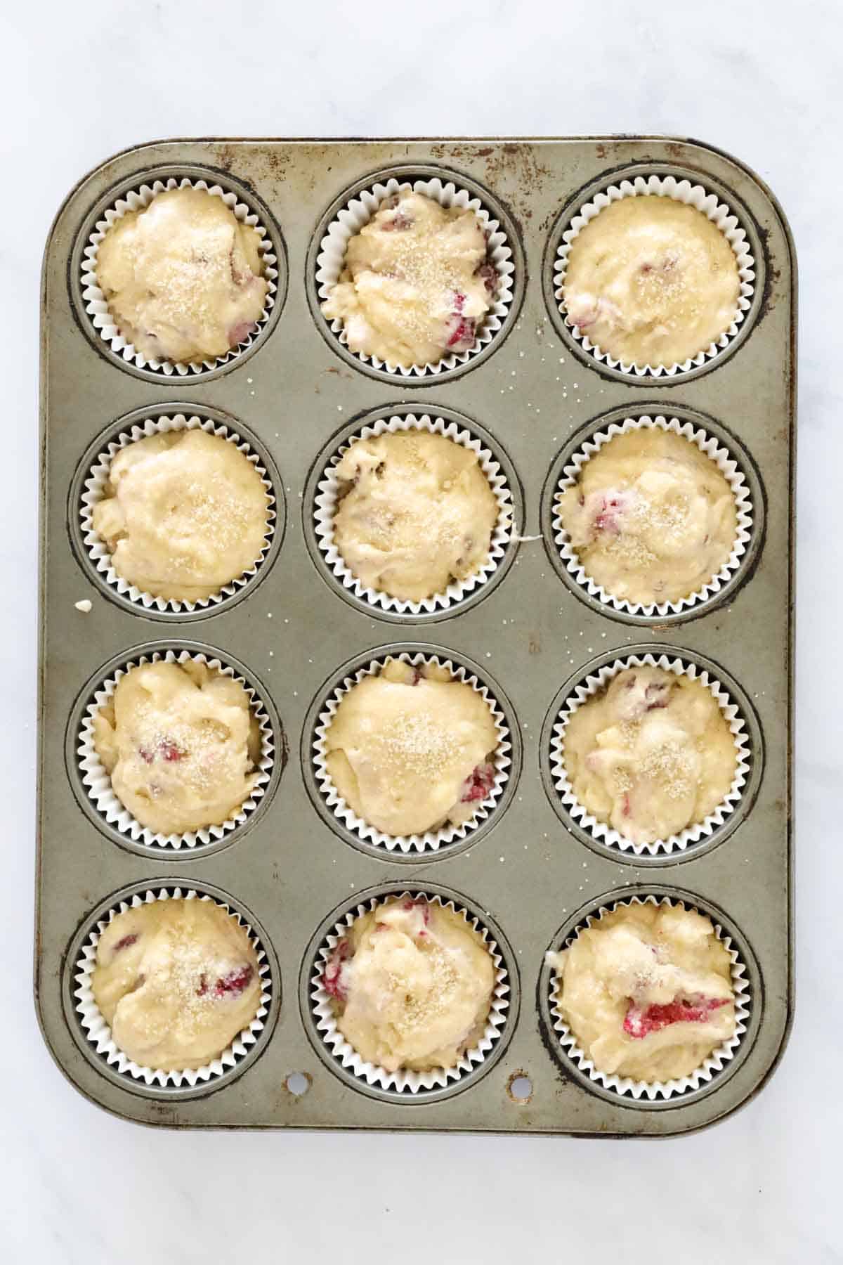 Mixture spooned into paper cases in a muffin tray.