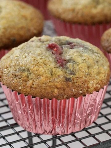 A close up of a banana and raspberry muffin in a pink case.