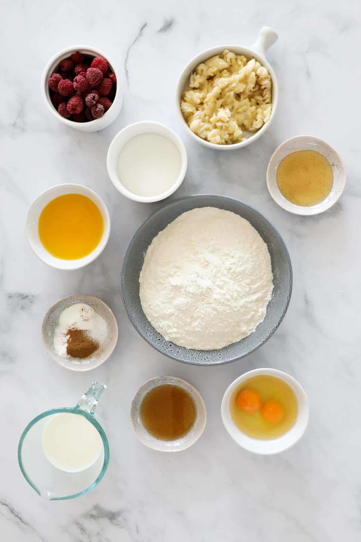 The ingredients for muffins set out on a marble bench top.
