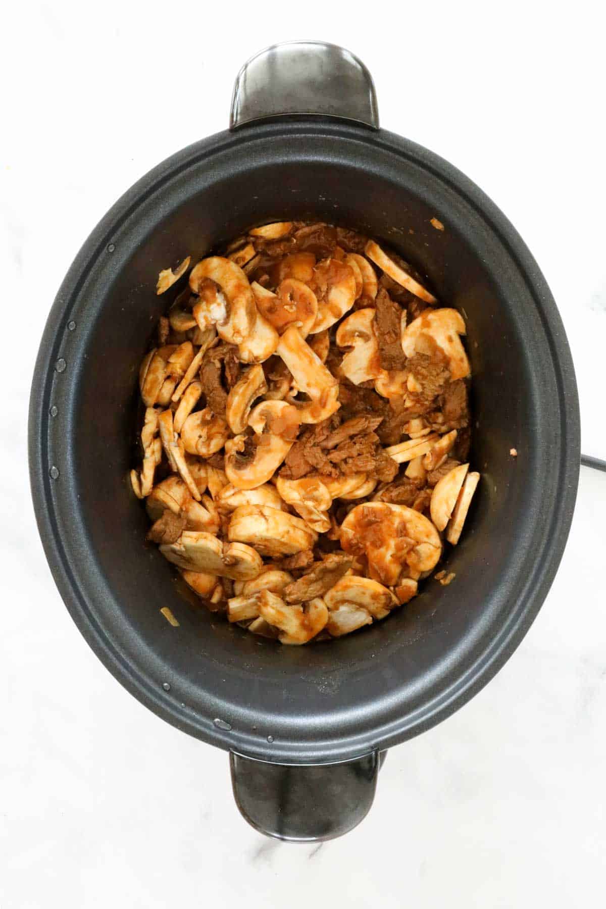 Sliced mushrooms added to slow cooker.