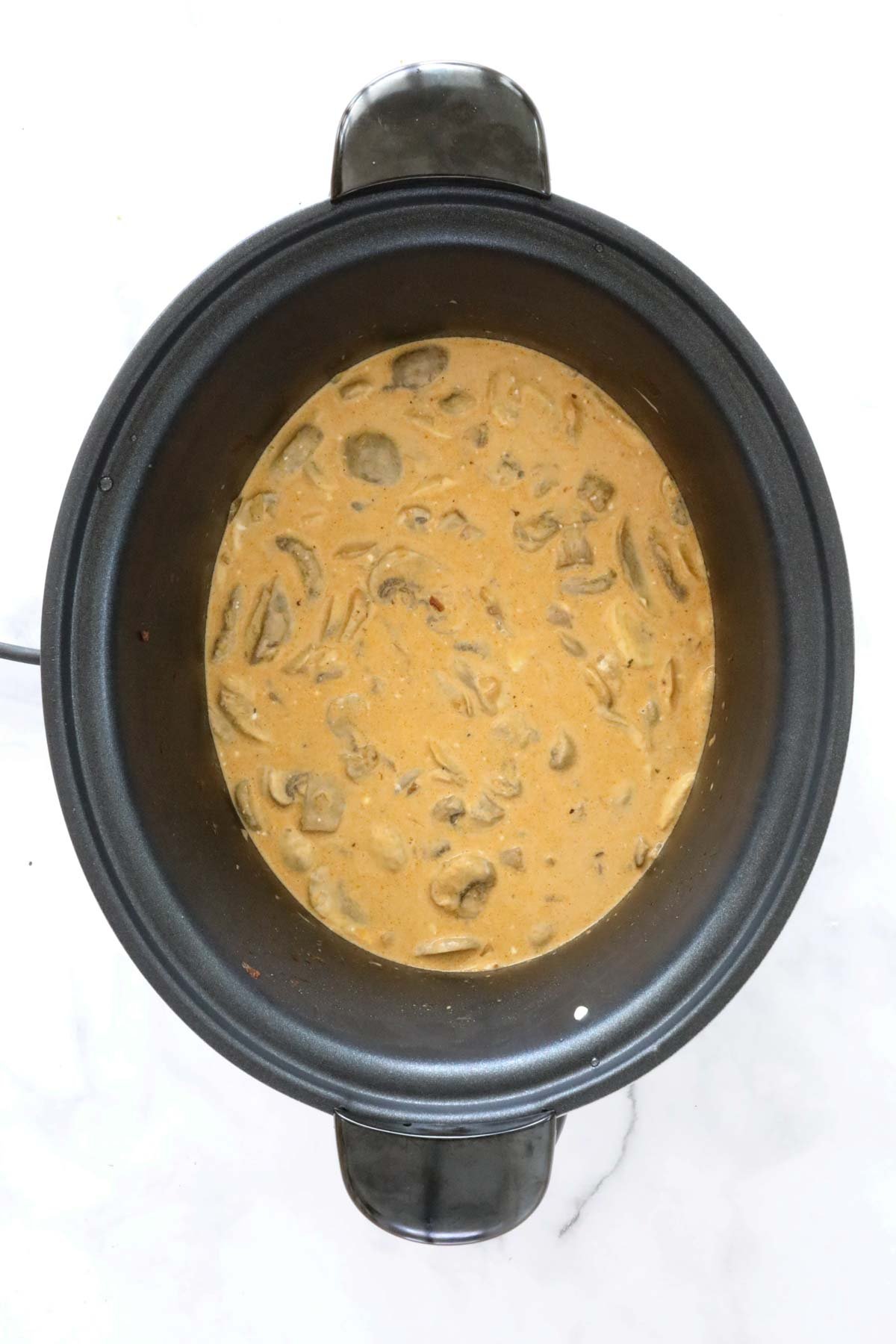 A creamy beef and mushroom dish simmering in slow cooker.