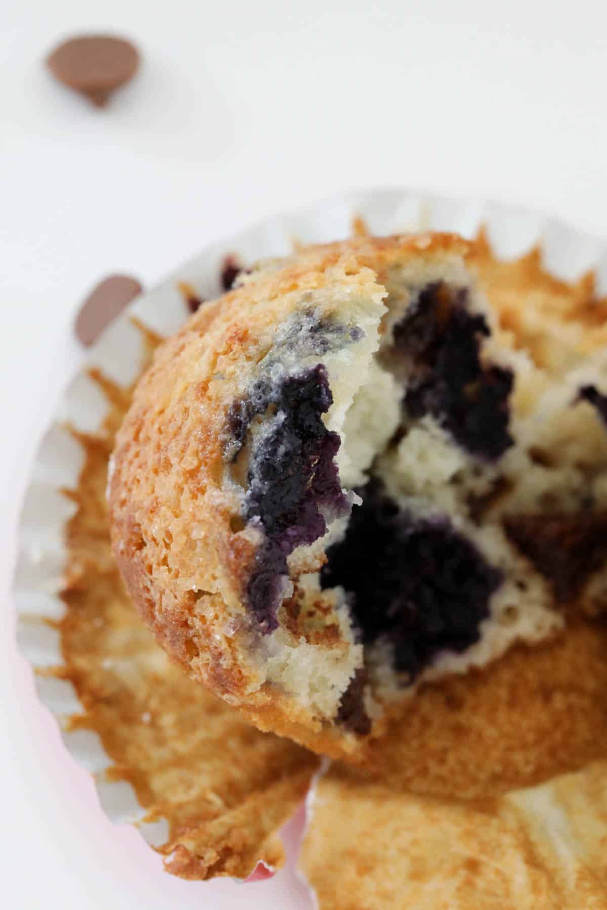 A close up of a half eaten blueberry chocolate chip muffin.