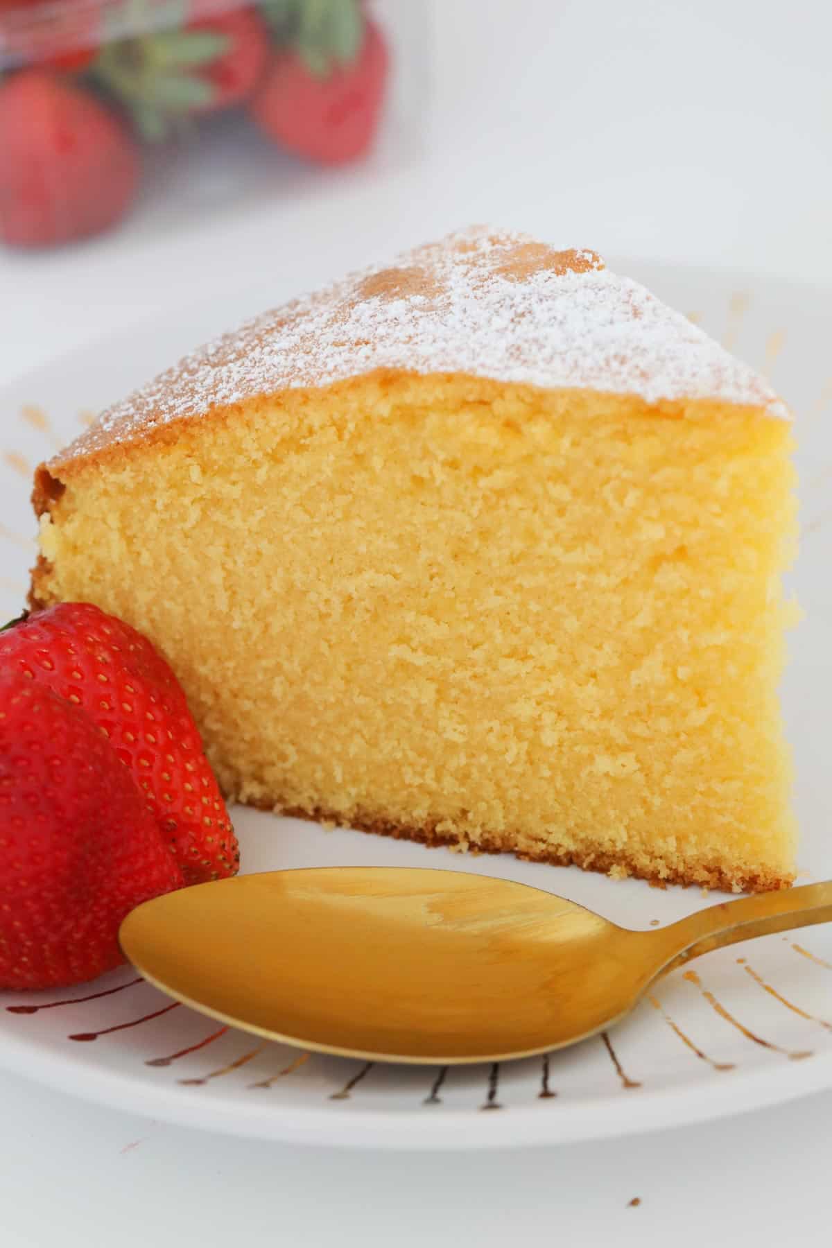 A slice of custard cake on a plate served with fresh strawberries.