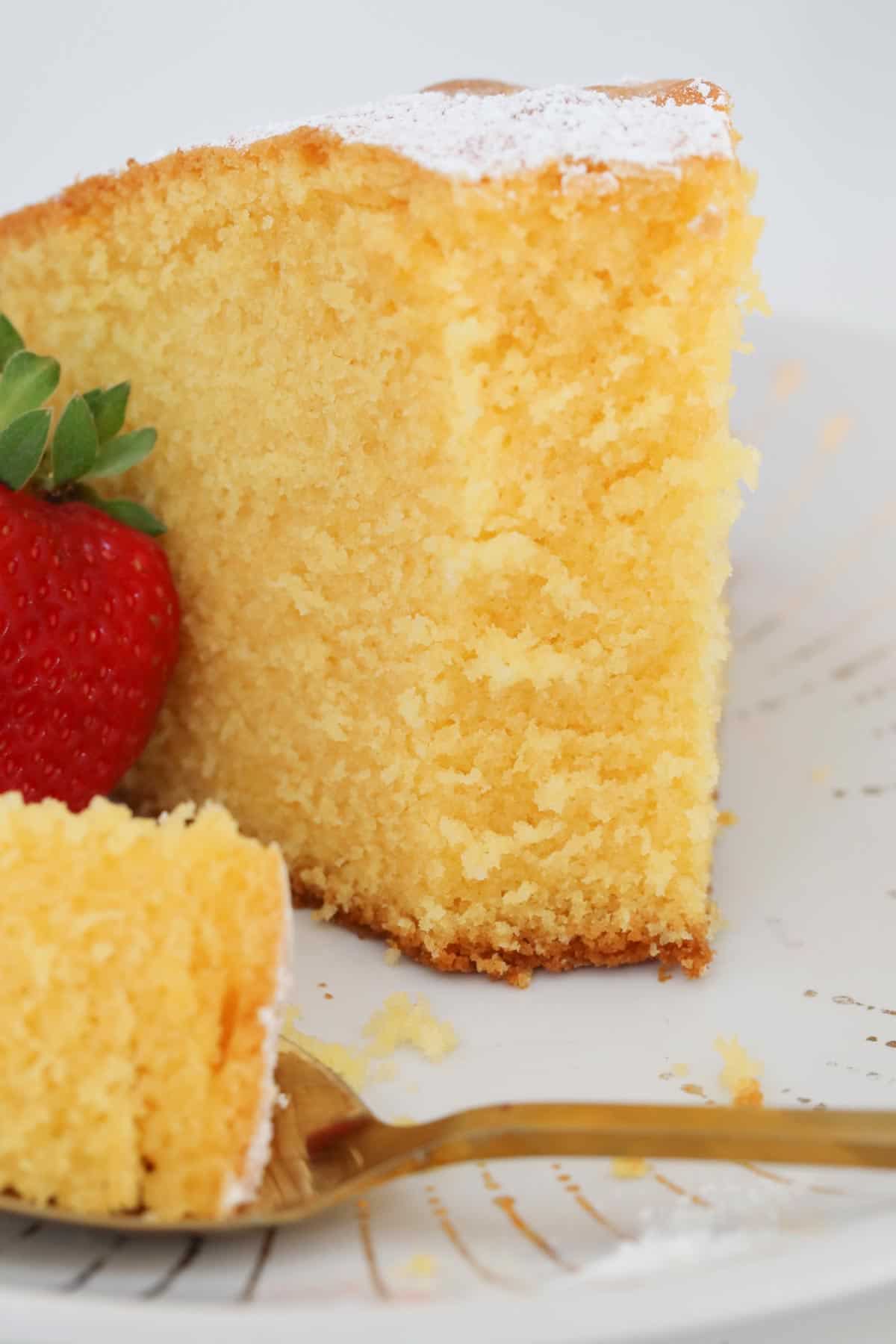 A slice of custard cake on a plate with a mouthful on a fork.