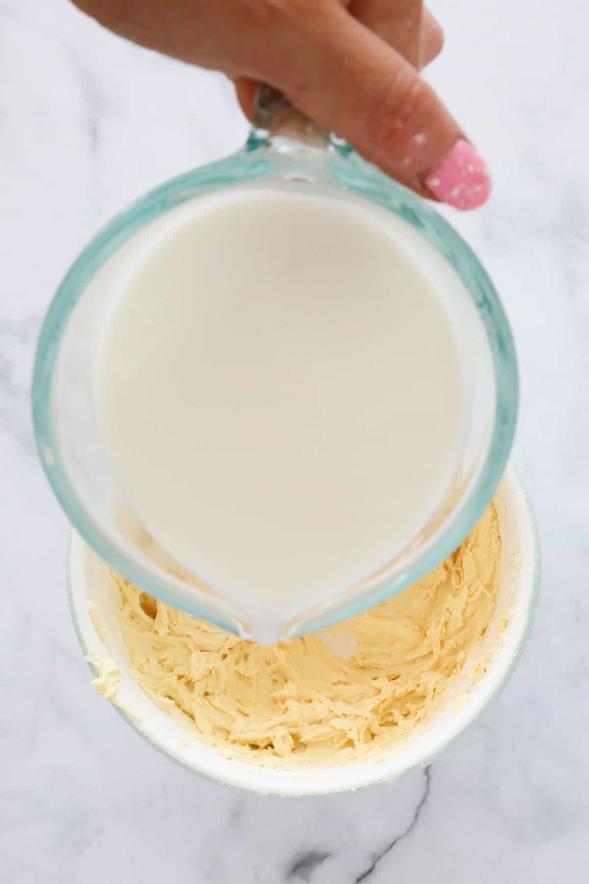 A jug of milk being poured into the batter.