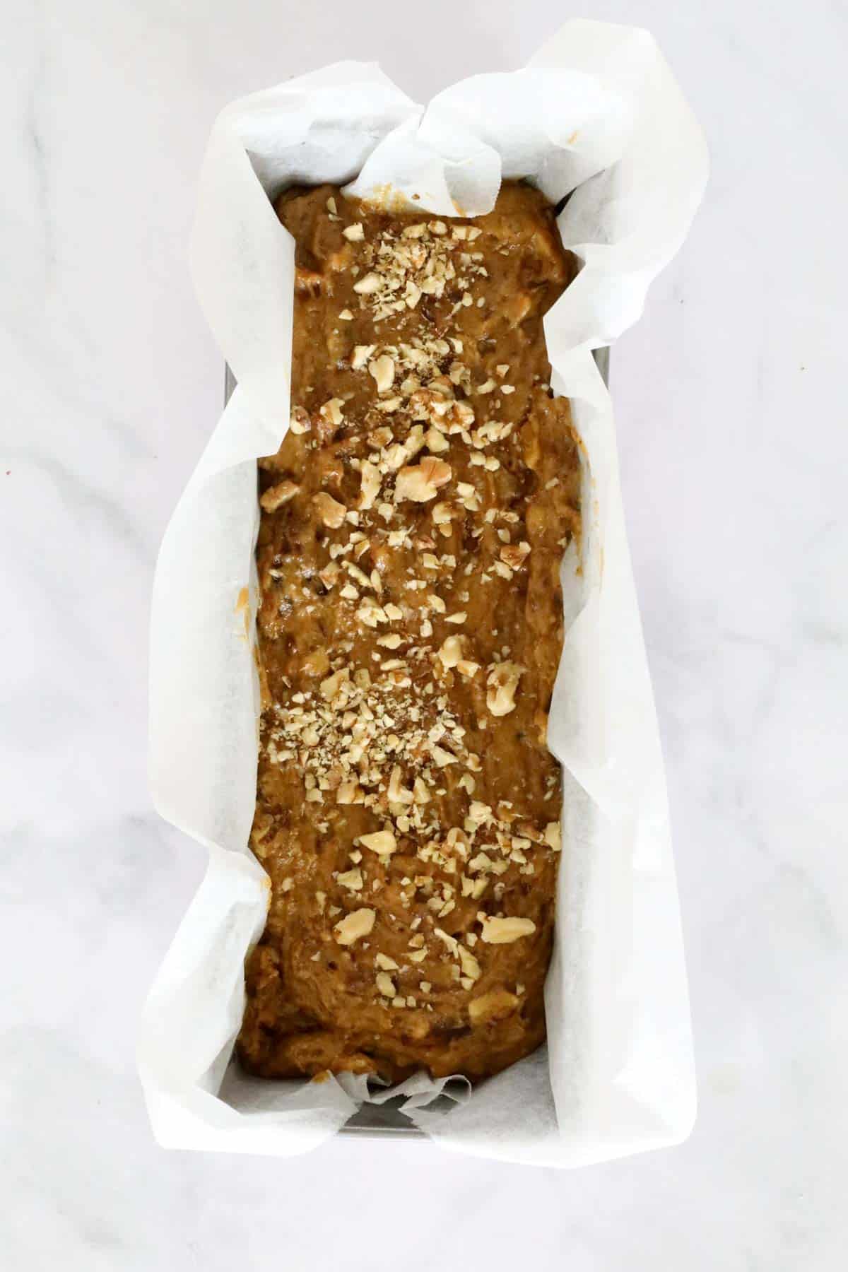 A loaf wrapped in baking paper and sprinkled with chopped walnuts.