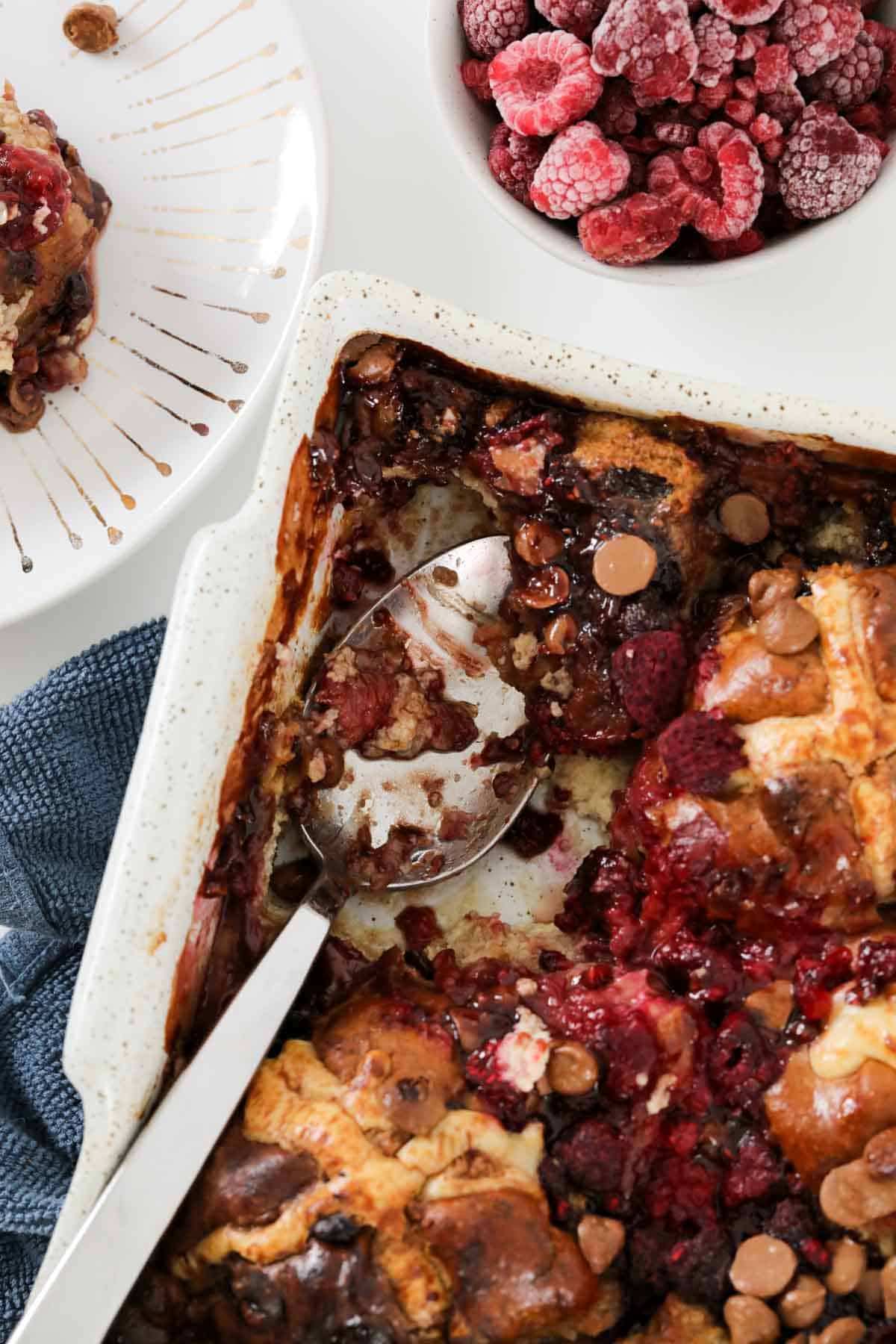 An overhead shot of hot cross buns baked into a raspberry pudding.