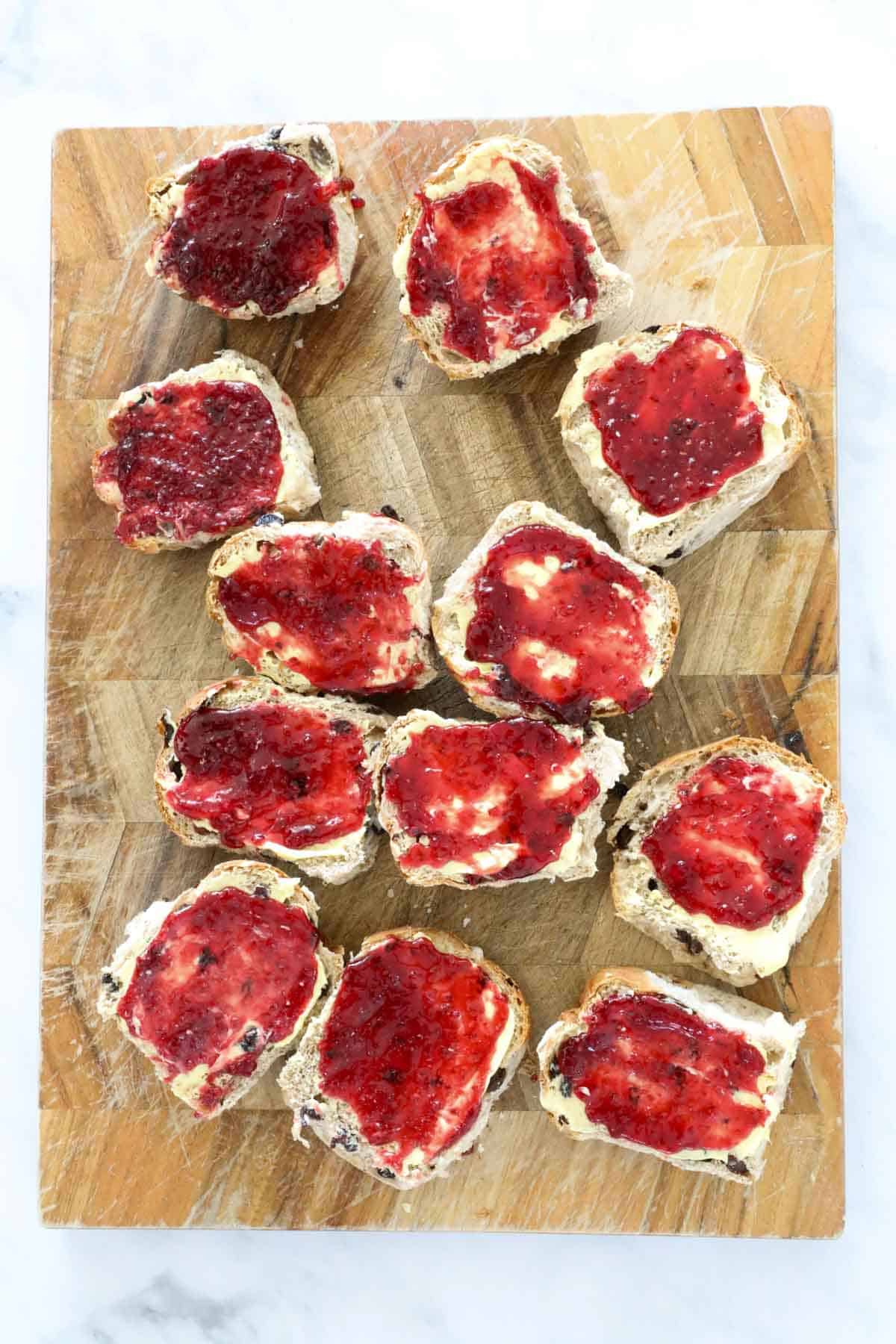 Hot cross buns cut in half and spread with butter and jam.