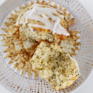 A half eaten lemon muffin with poppy seeds and a white glaze on top.