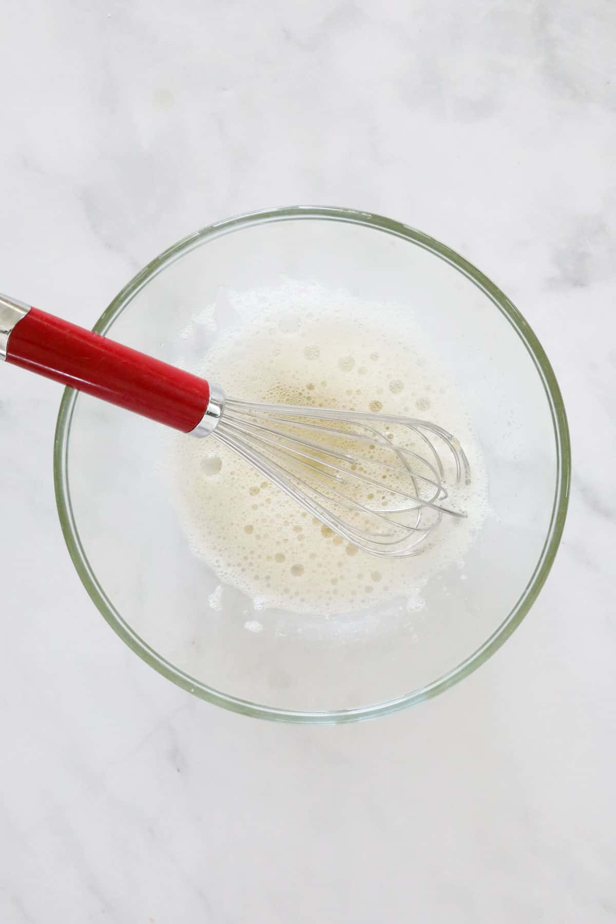 Gelatine in a glass bowl with a whisk.