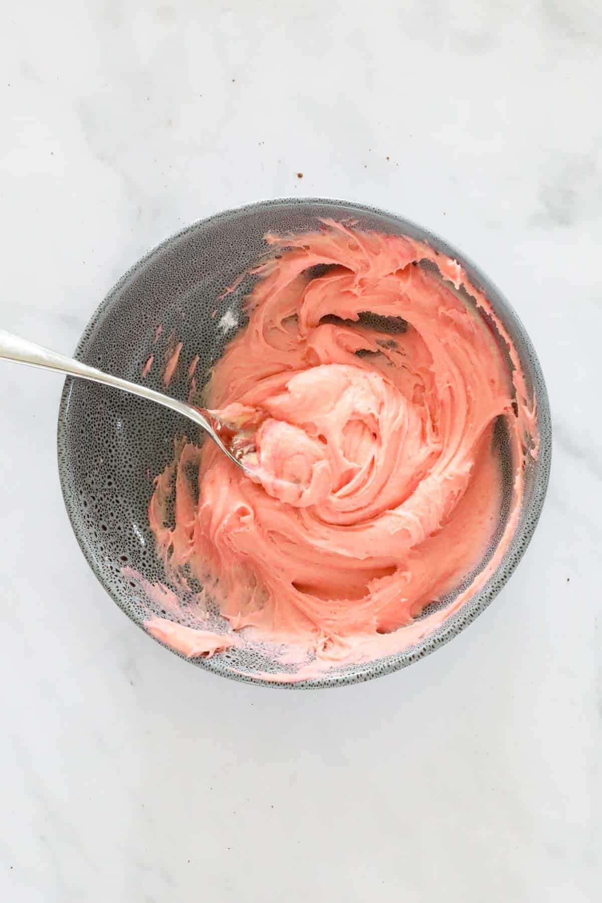 Pink cake batter in a bowl with a spoon.