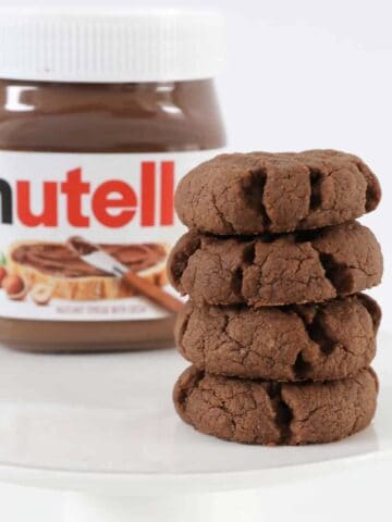 A stack of Nutella cookies in front of a jar of Nutella.