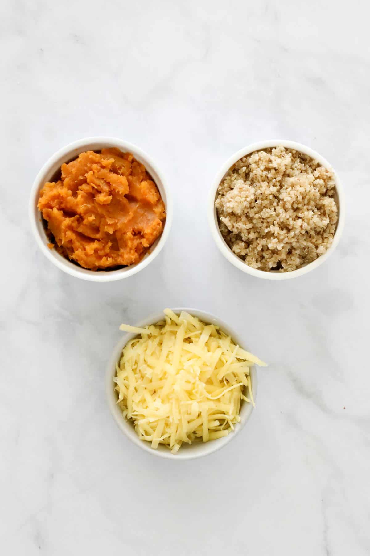 The three ingredients - sweet potato, quinoa and cheese, in individual bowls.
