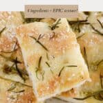 Pieces of baked focaccia sprinkled with rosemary leaves and sea salt.