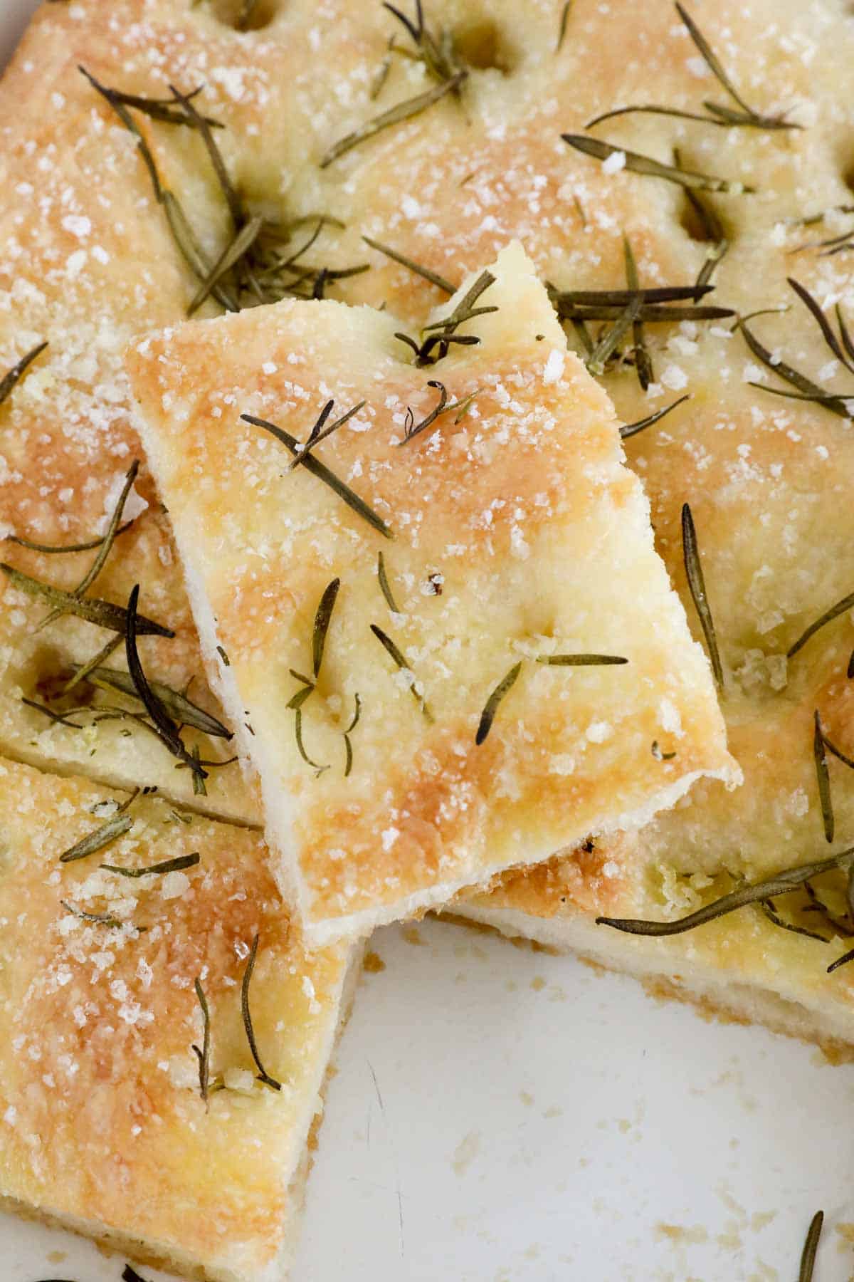 A piece of homemade focaccia with rosemary and sea salt on top.