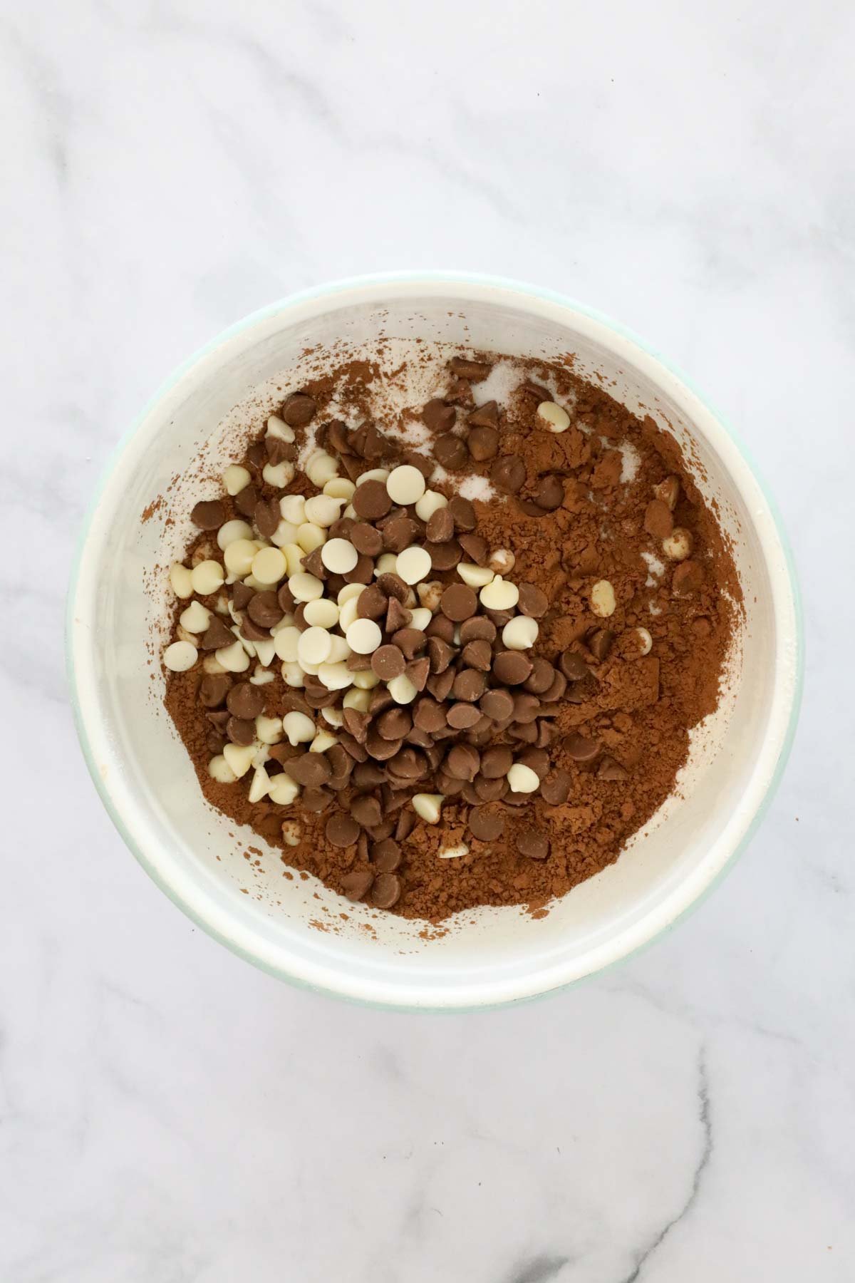 Chocolate chips, cocoa powder and sugar added to flour in a mixing bowl.