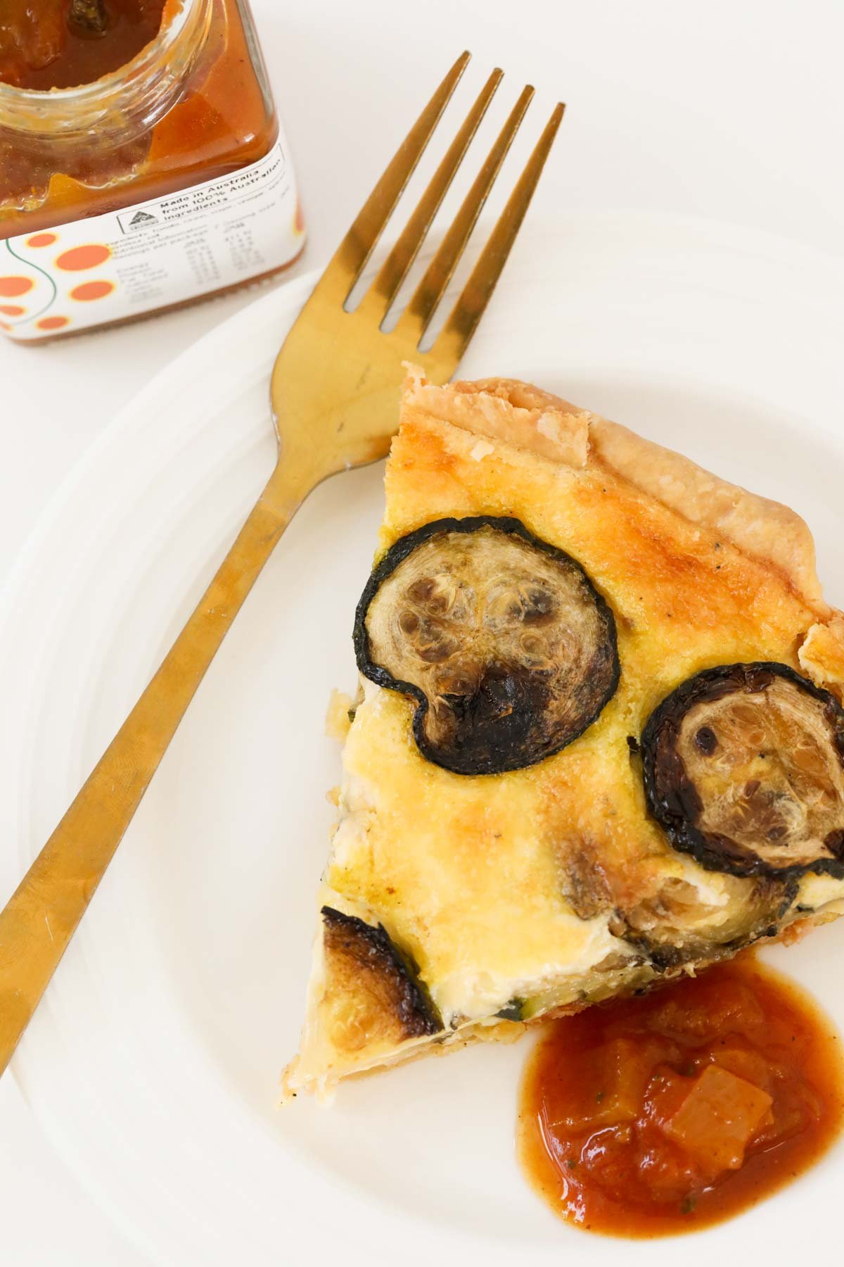 A slice of quiche with a fork on a plate.