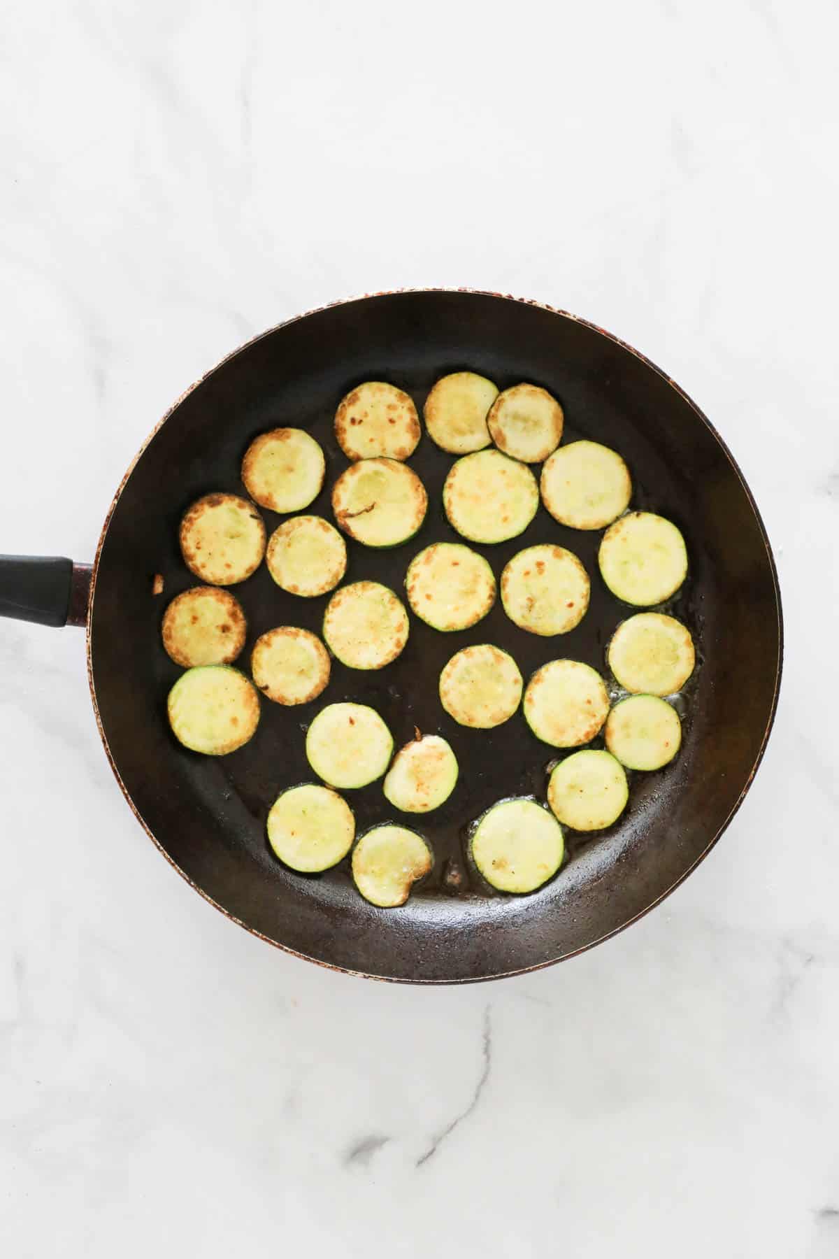 Zucchini slices in a frying pan.