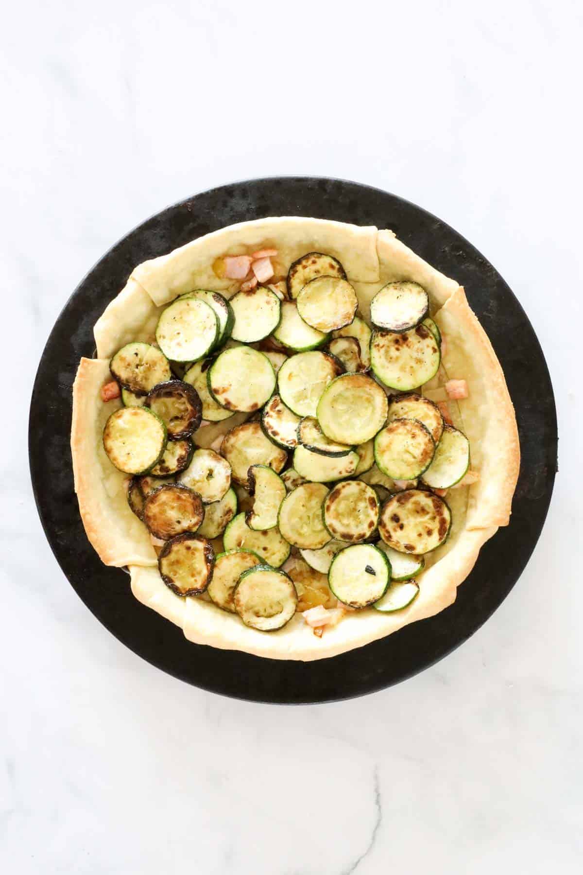 Cooked zucchini slices added to pie crust.