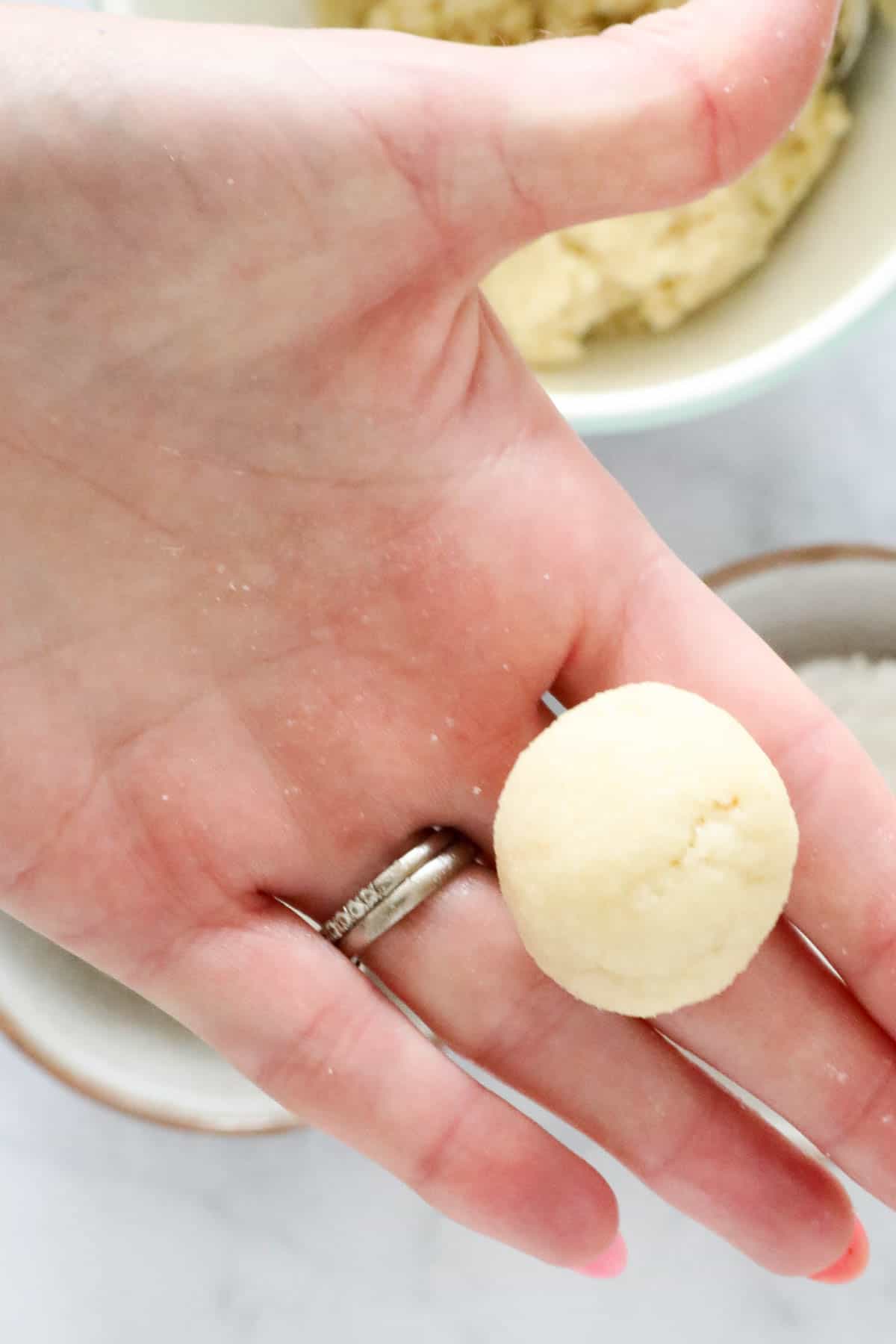 An cookie dough ball held up in a hand.