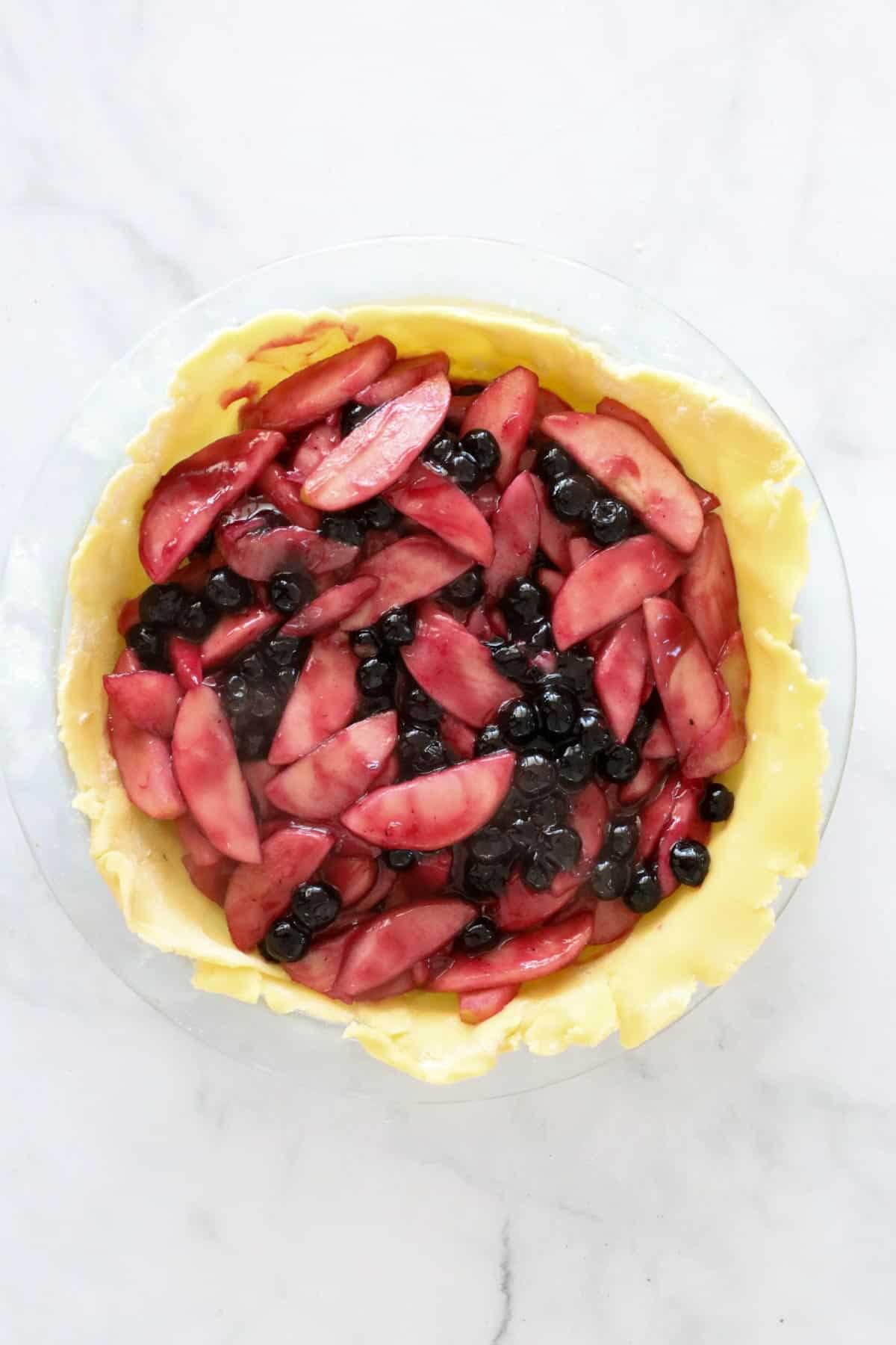 Unbaked pie crust filled with cooked apples and blueberries