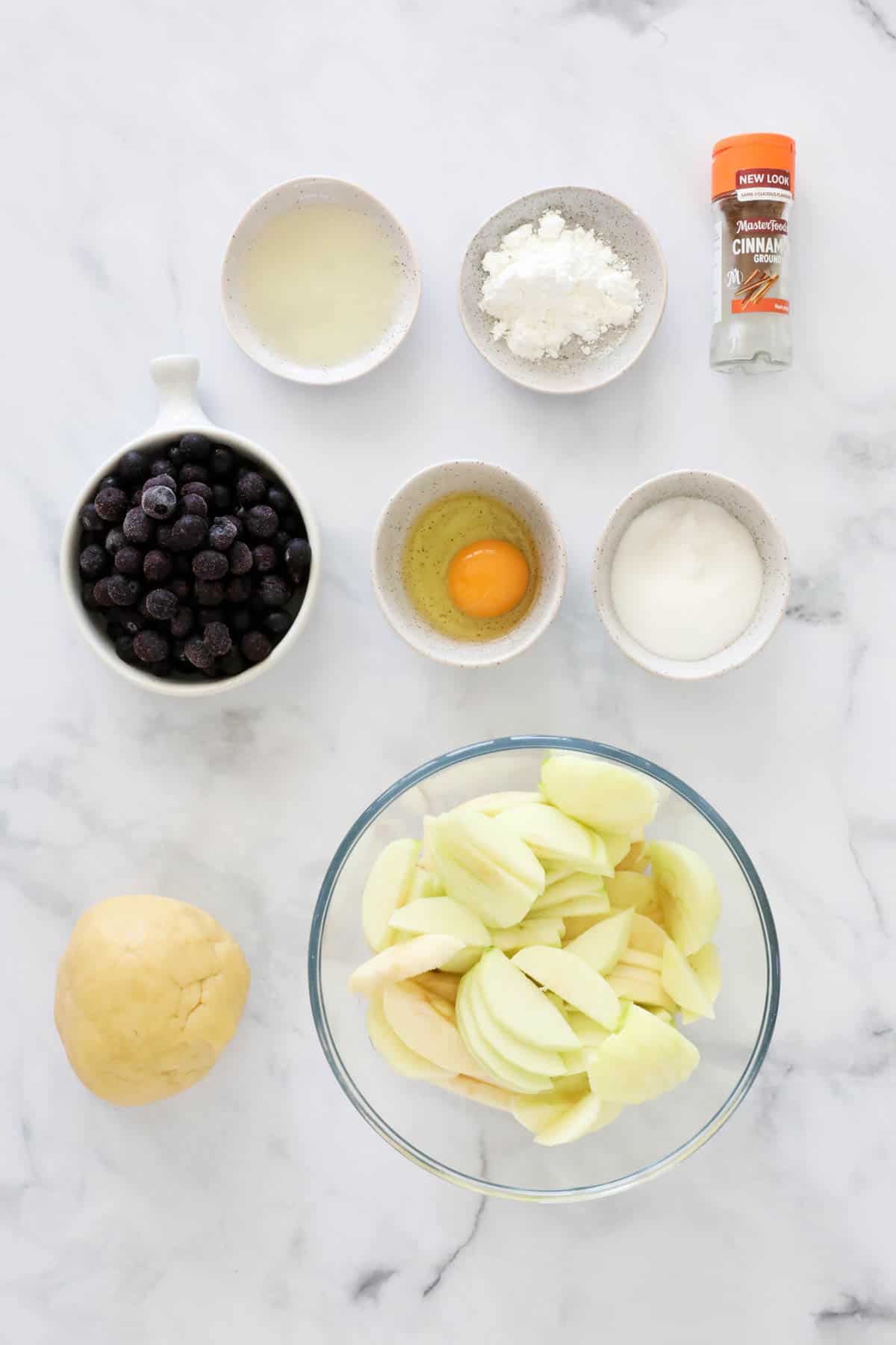 Ingredients needed to make the filling of the apple and blueberry pie weighed out and placed in individual bowls.