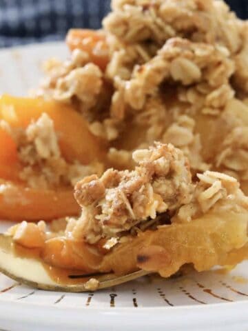 A plate of soft apricots with a crunchy crumble on top.
