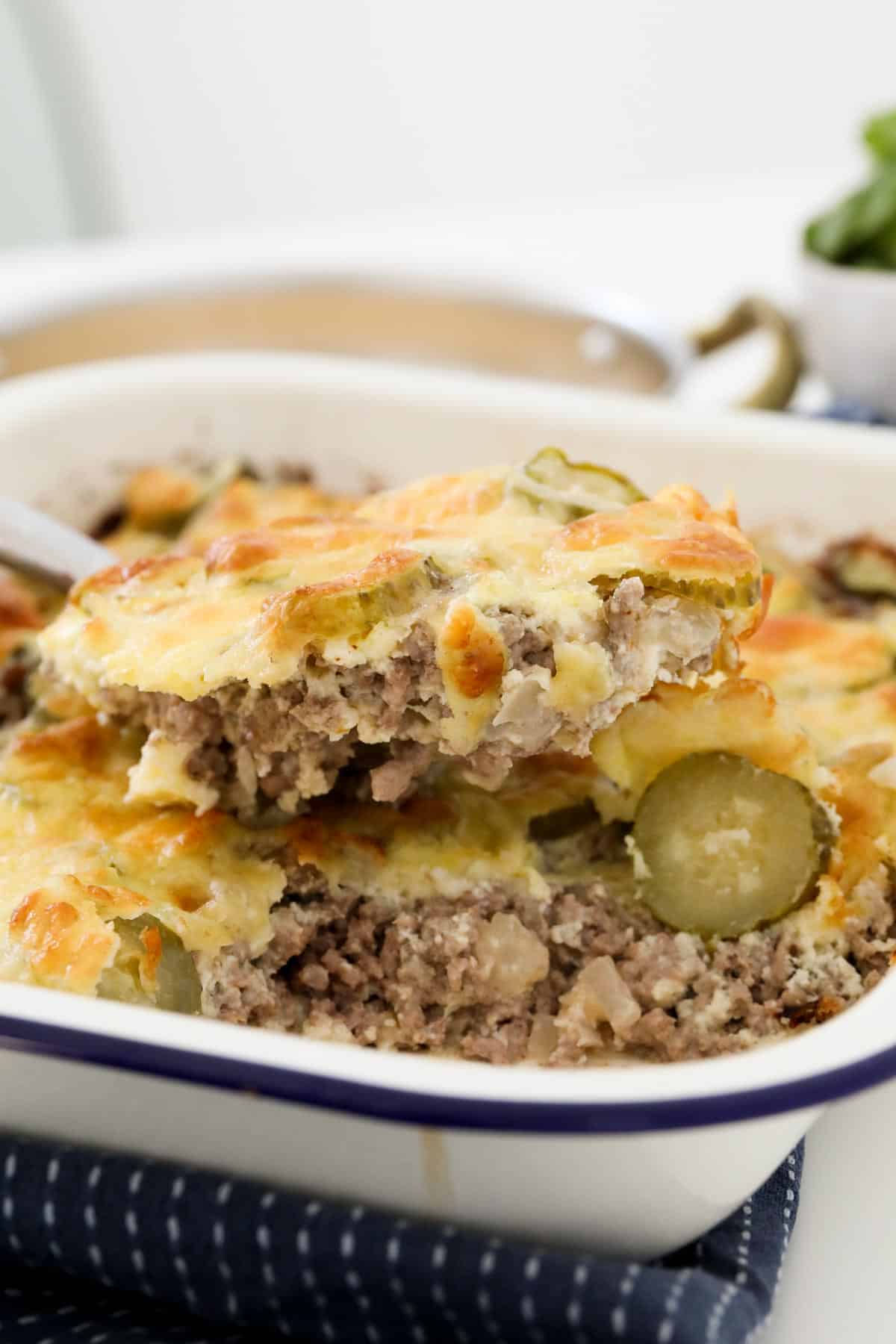 A spoon lifting a cheesy beef bake out of a dish.