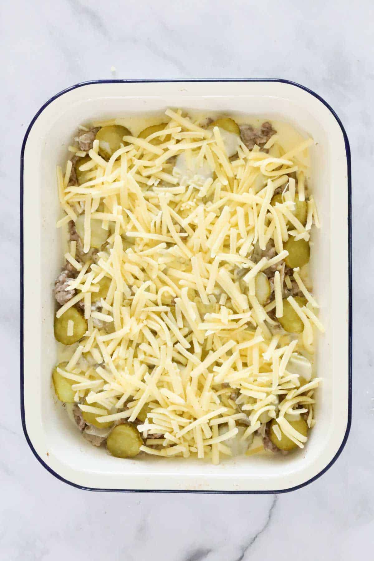 Sliced pickles covered in grated cheese.