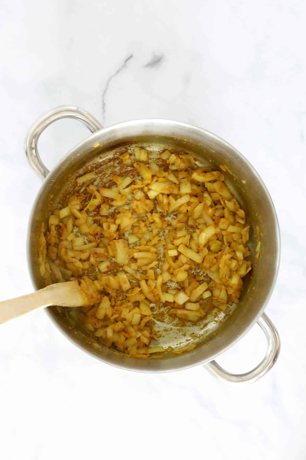 A pot with onion and spices being sauteed.