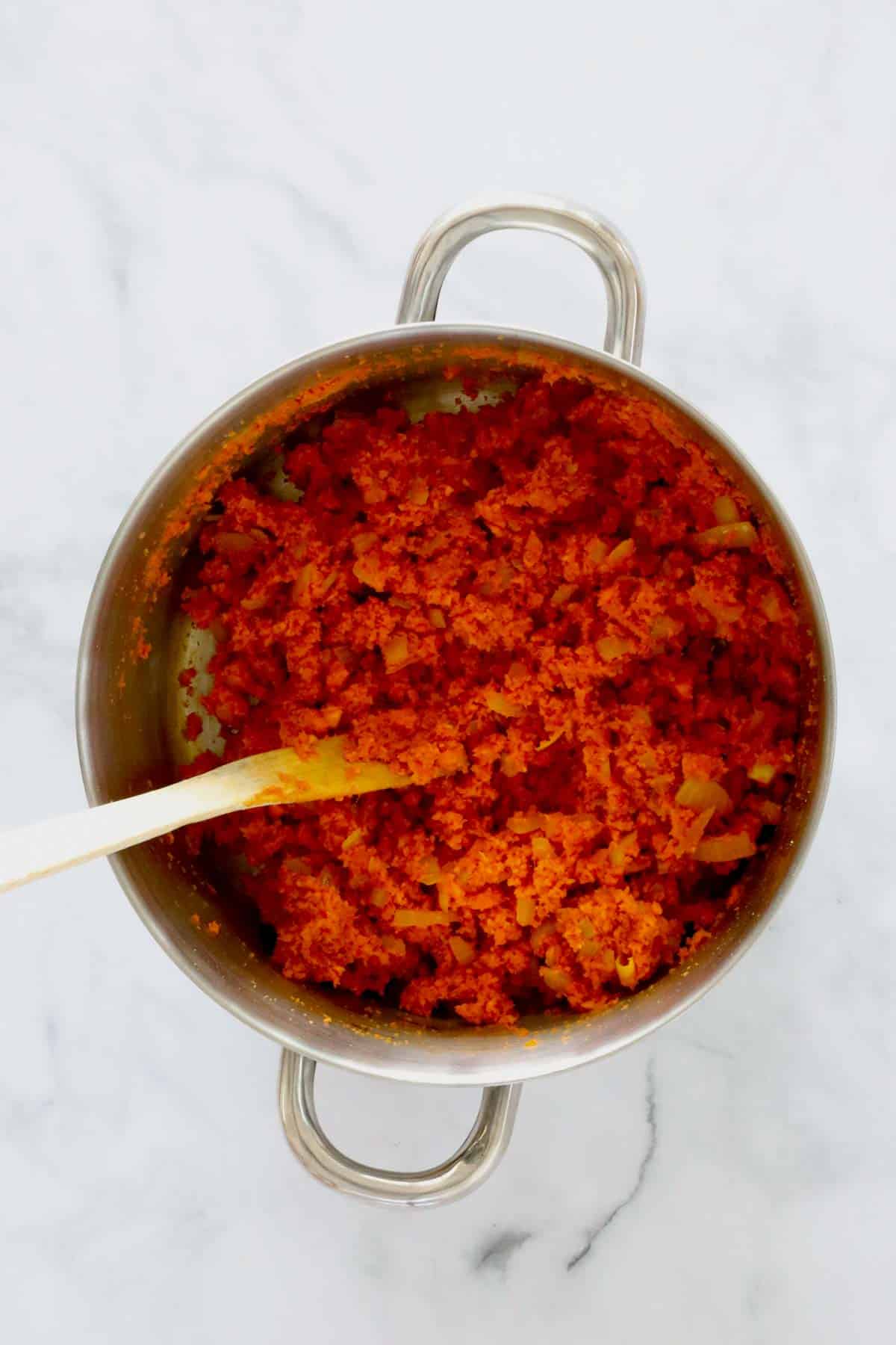 Grated carrot and tomato paste in a pot.