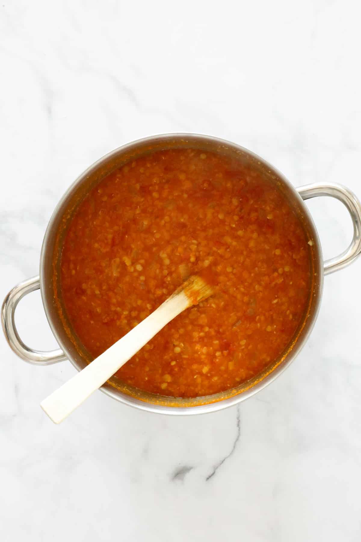 Lentils and stock added to carrot and spices in a pot.