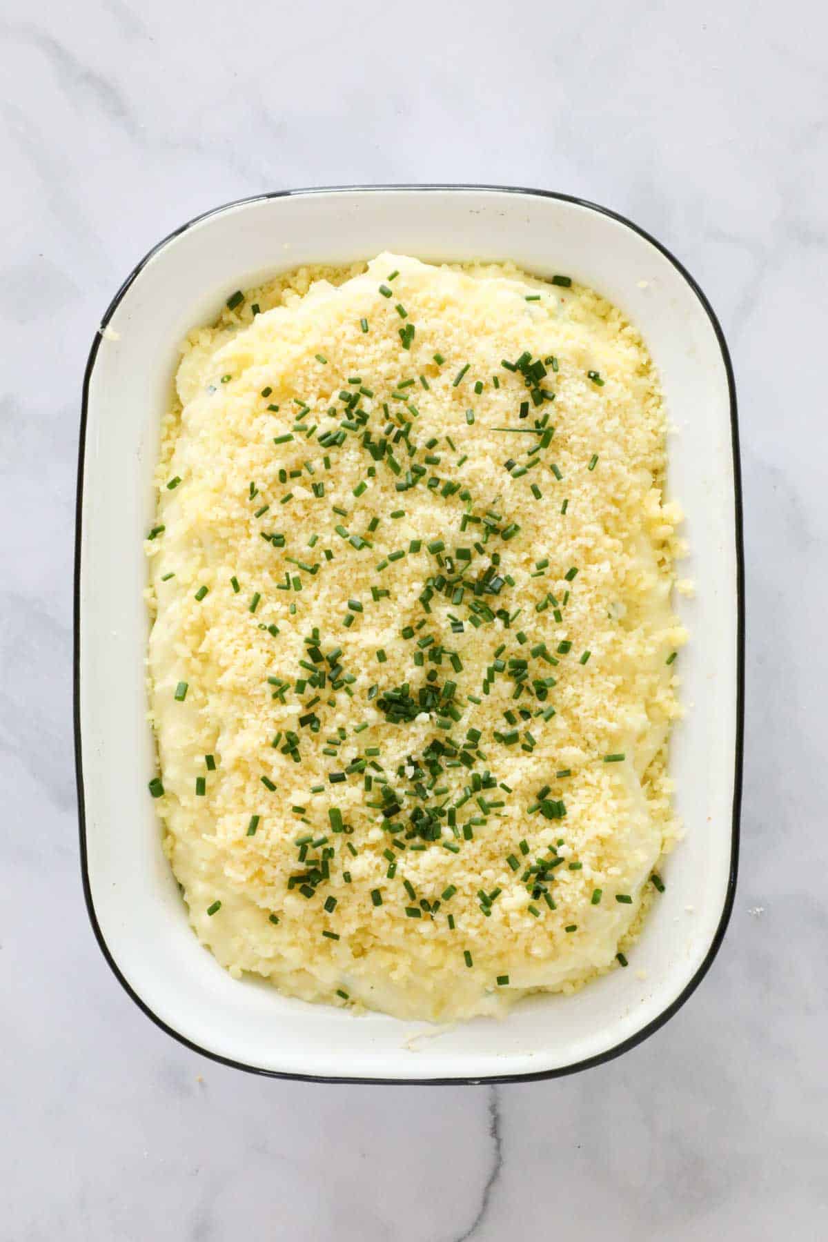 Cheese and chives sprinkled over baking dish.