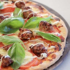 A pizza with pork meatballs, tomato, basil, cheese and kewpie.